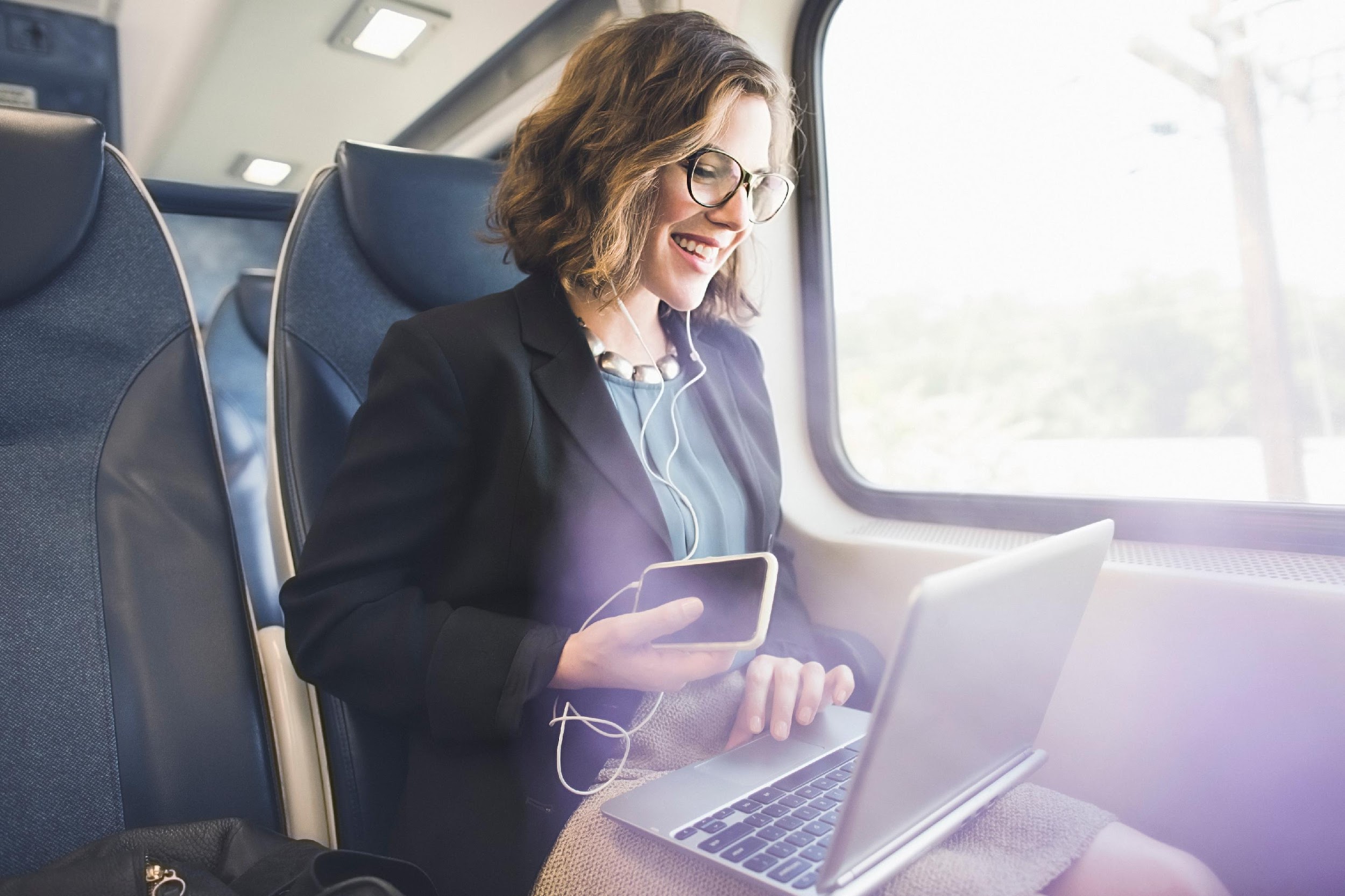 White woman on airplane looking at laptop